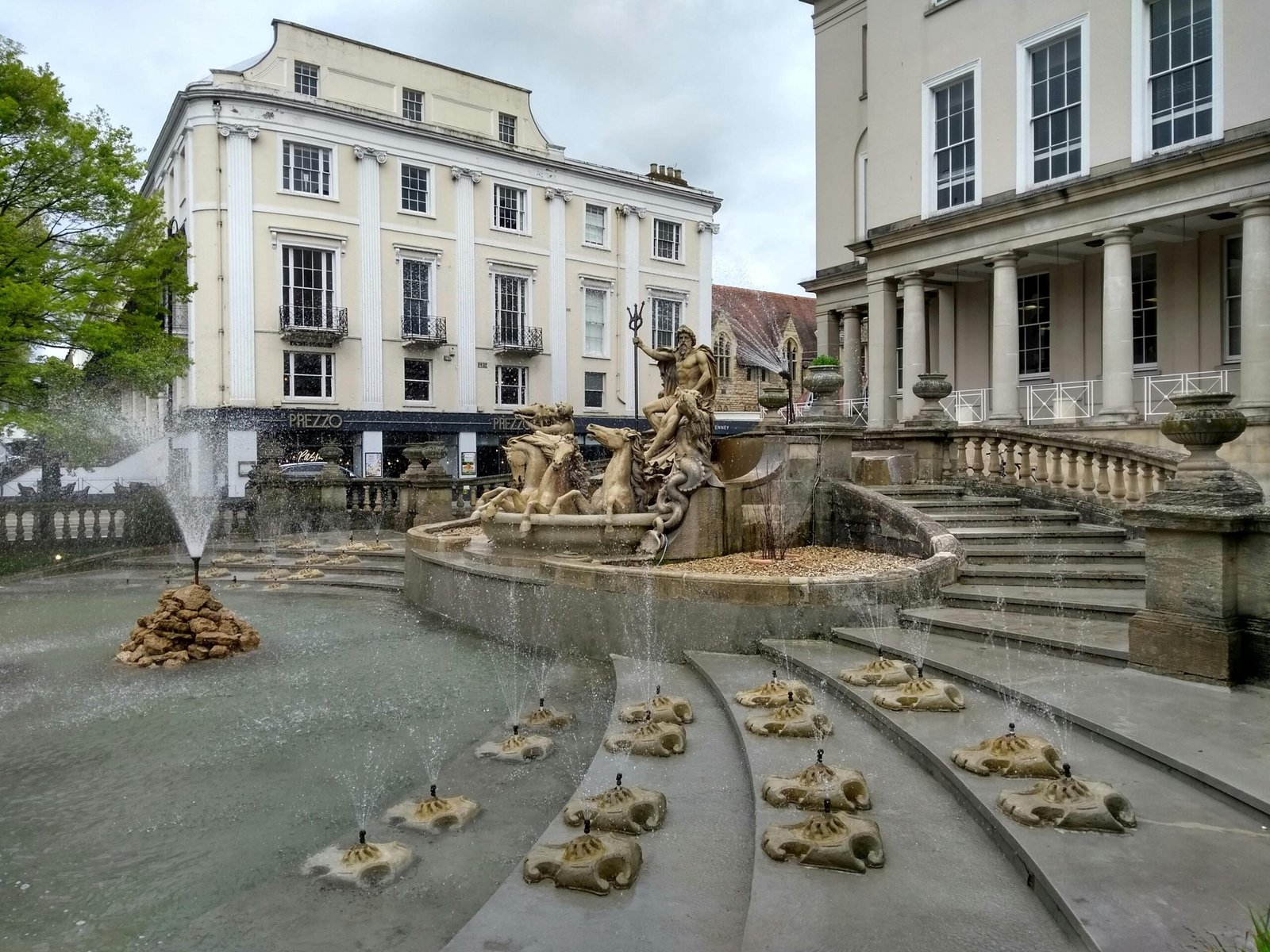 Elegant fountain in front of historic buildings in Cheltenham, England.