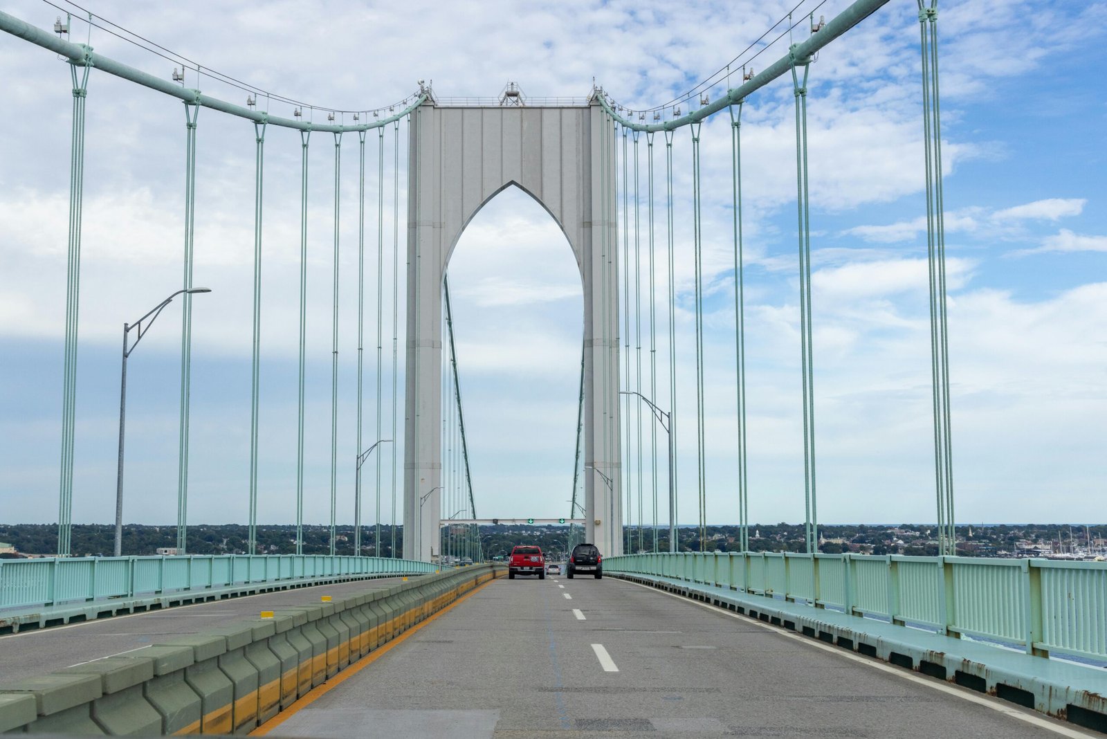 Suspension bridge in Newport, RI with vehicles on a sunny day.