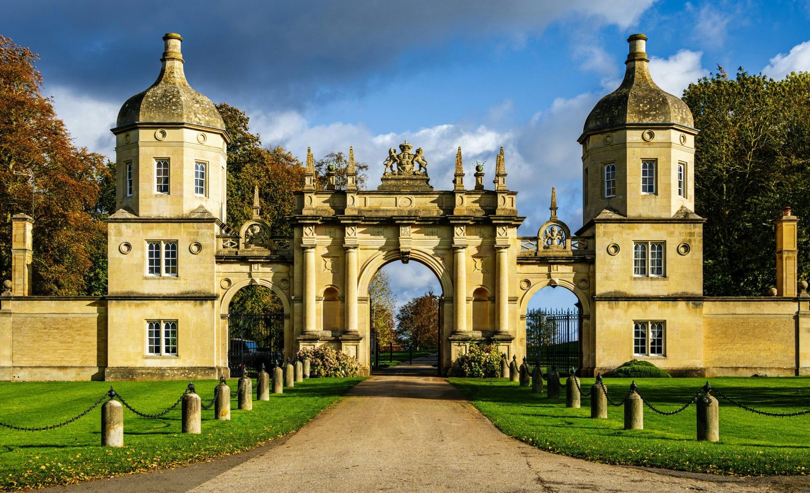 Grand entrance gate in Peterborough surrounded by lush greenery.