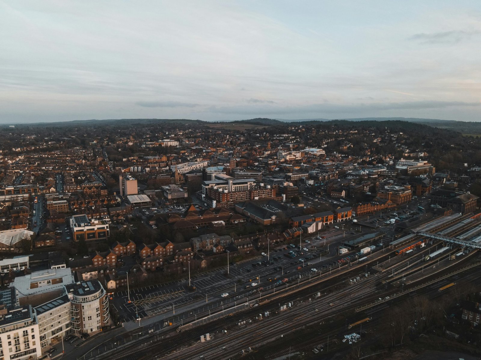 Aerial shot of Guildford, UK, showcasing urban cityscape and train tracks at dusk.