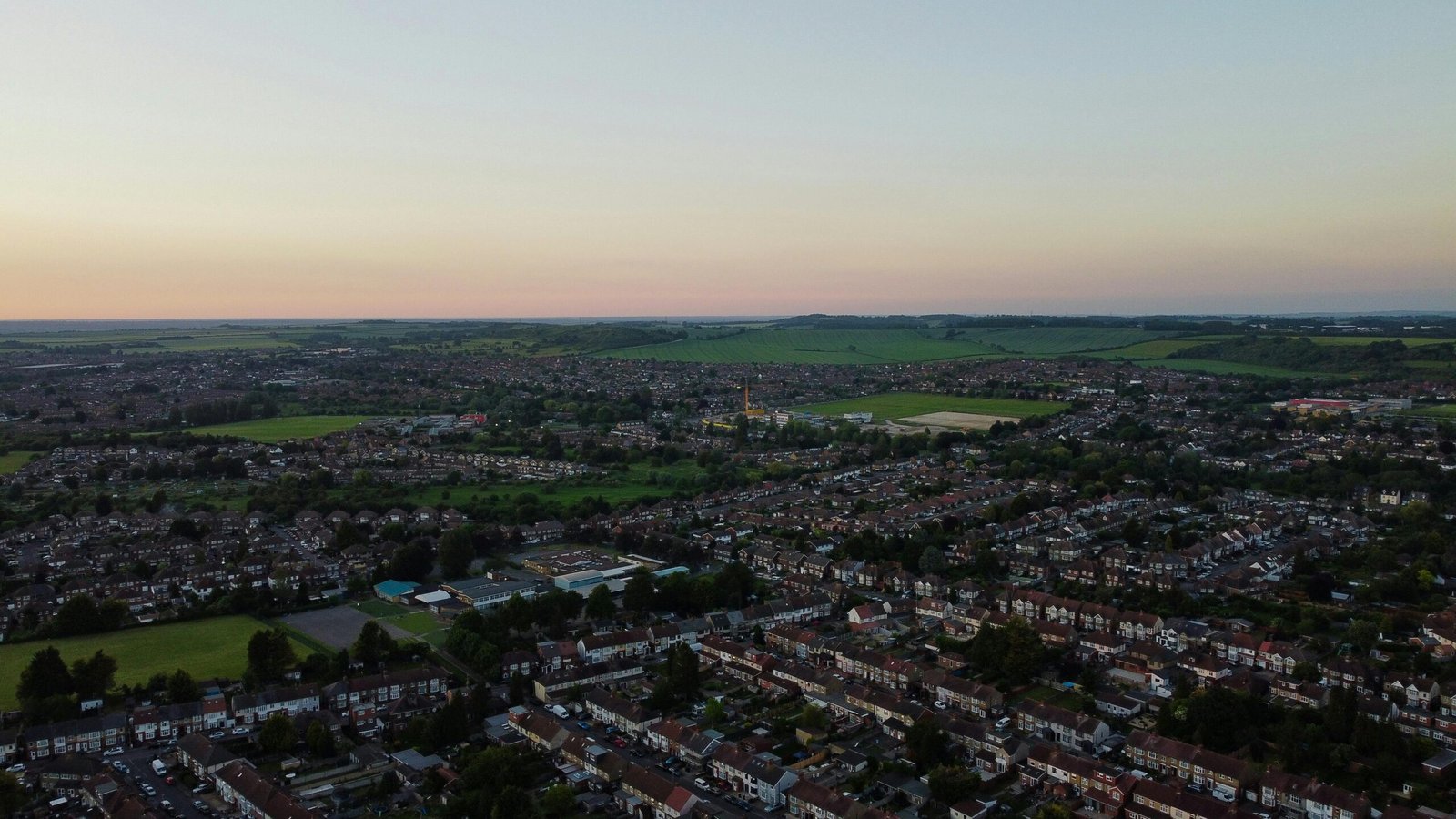 Expansive drone view of Luton's urban landscape at dusk showcasing vast residential areas.